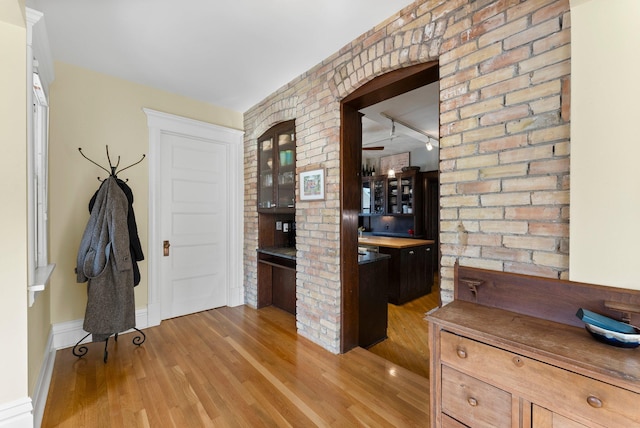 bar featuring brick wall and light wood-style floors