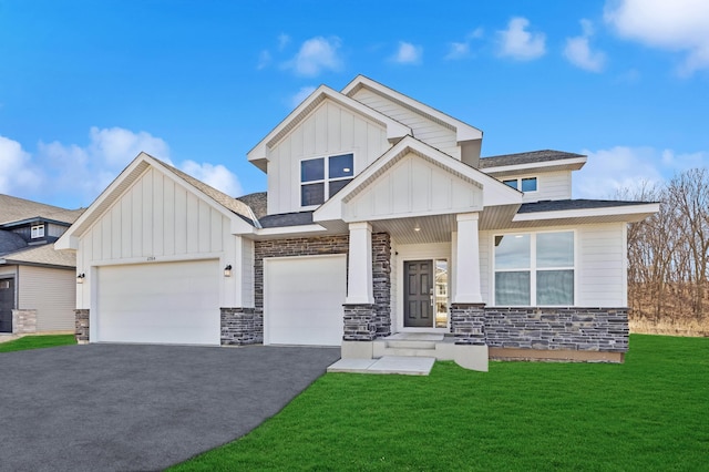 view of front of house featuring an attached garage, driveway, stone siding, a front lawn, and board and batten siding