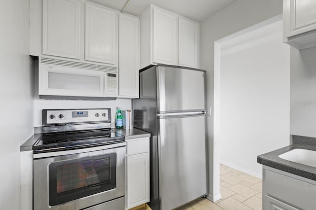 kitchen featuring dark countertops, white cabinetry, appliances with stainless steel finishes, and baseboards