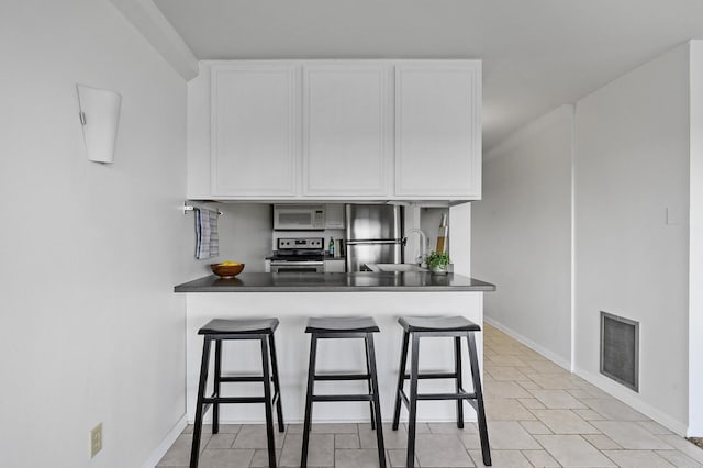 kitchen with dark countertops, white cabinetry, visible vents, and stainless steel appliances