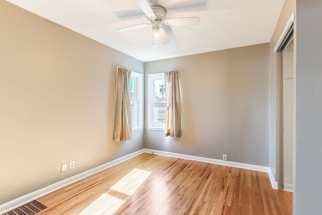 unfurnished room featuring ceiling fan, visible vents, light wood-style flooring, and baseboards