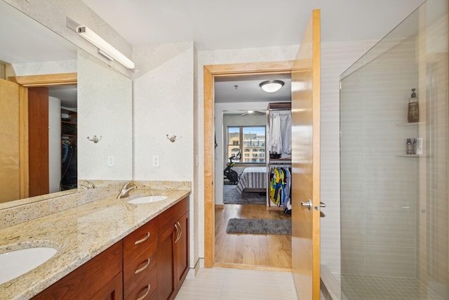 bathroom with a spacious closet, a sink, a shower stall, and double vanity