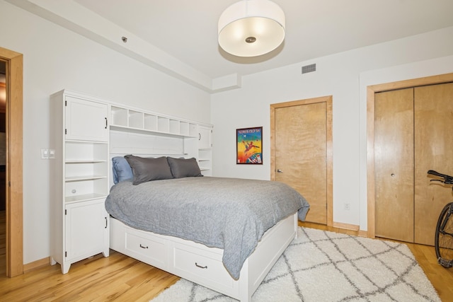 bedroom with light wood-type flooring, visible vents, and baseboards