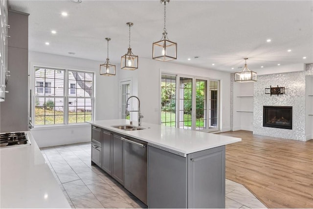 kitchen featuring stainless steel appliances, light countertops, gray cabinetry, open floor plan, and a sink