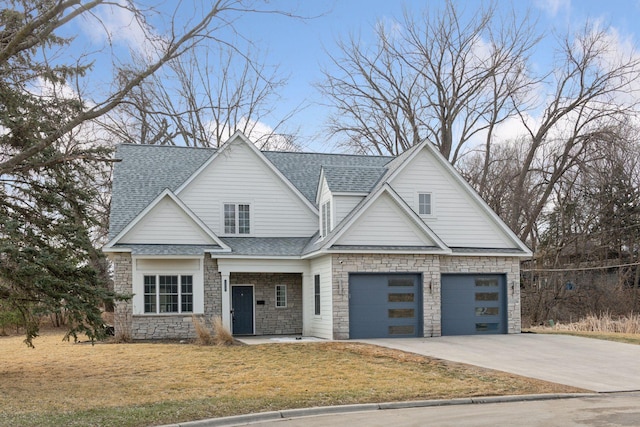 view of front of home featuring a garage, driveway, stone siding, roof with shingles, and a front lawn