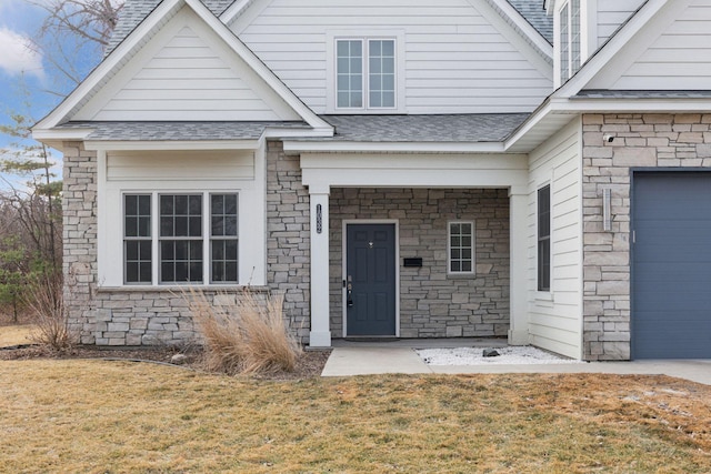 entrance to property featuring stone siding, roof with shingles, and a yard