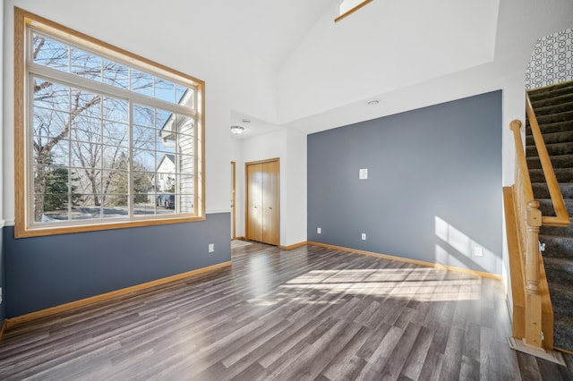 interior space featuring stairs, high vaulted ceiling, wood finished floors, and baseboards