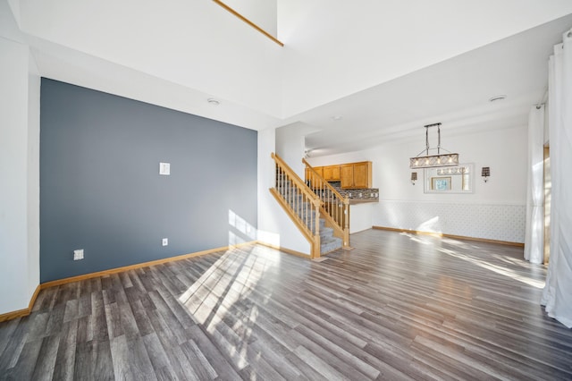 unfurnished living room with baseboards, stairway, and wood finished floors