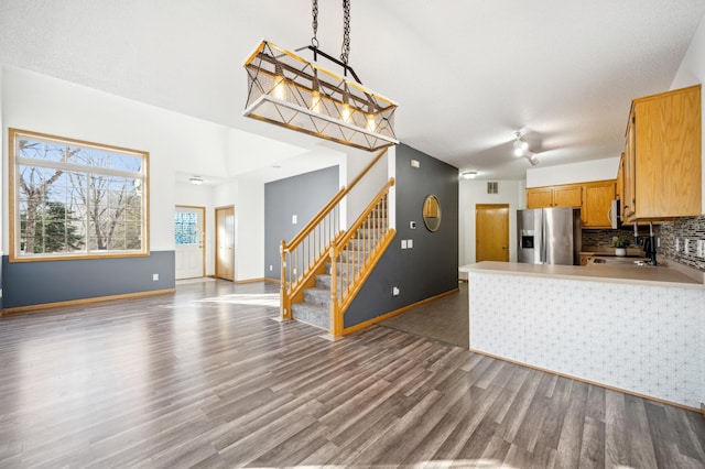 kitchen with dark wood-style floors, stainless steel appliances, light countertops, backsplash, and open floor plan