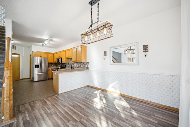 kitchen with dark wood finished floors, stainless steel appliances, light countertops, a peninsula, and wallpapered walls