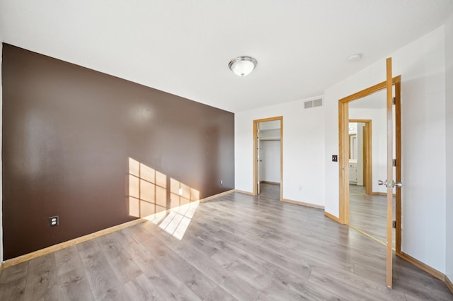 spare room with visible vents, baseboards, and wood finished floors