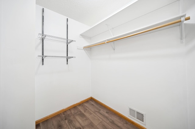 spacious closet featuring dark wood-type flooring and visible vents