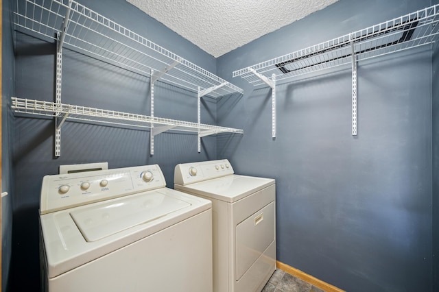 laundry room with laundry area, independent washer and dryer, a textured ceiling, and baseboards