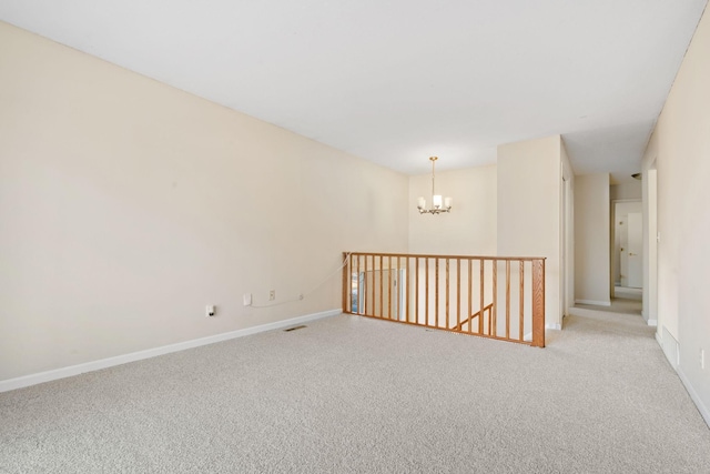 unfurnished room with light colored carpet, baseboards, and an inviting chandelier