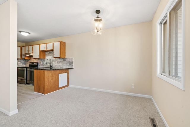 kitchen with light carpet, stainless steel electric stove, visible vents, decorative backsplash, and dark countertops