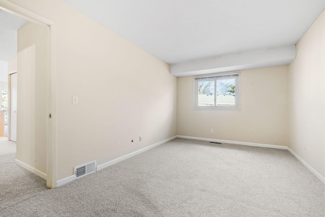 carpeted spare room with visible vents and baseboards