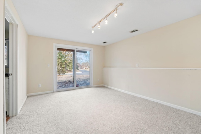 spare room with track lighting, baseboards, visible vents, and carpet flooring