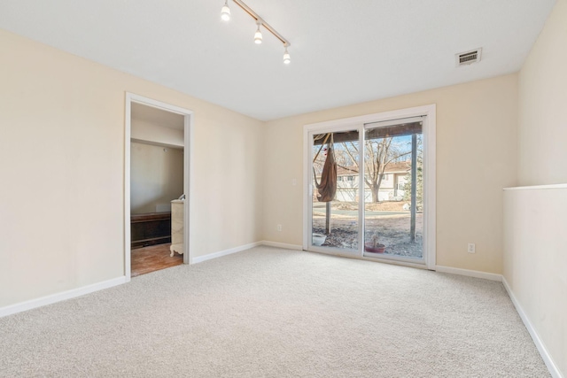 unfurnished bedroom featuring visible vents, baseboards, rail lighting, access to outside, and carpet floors