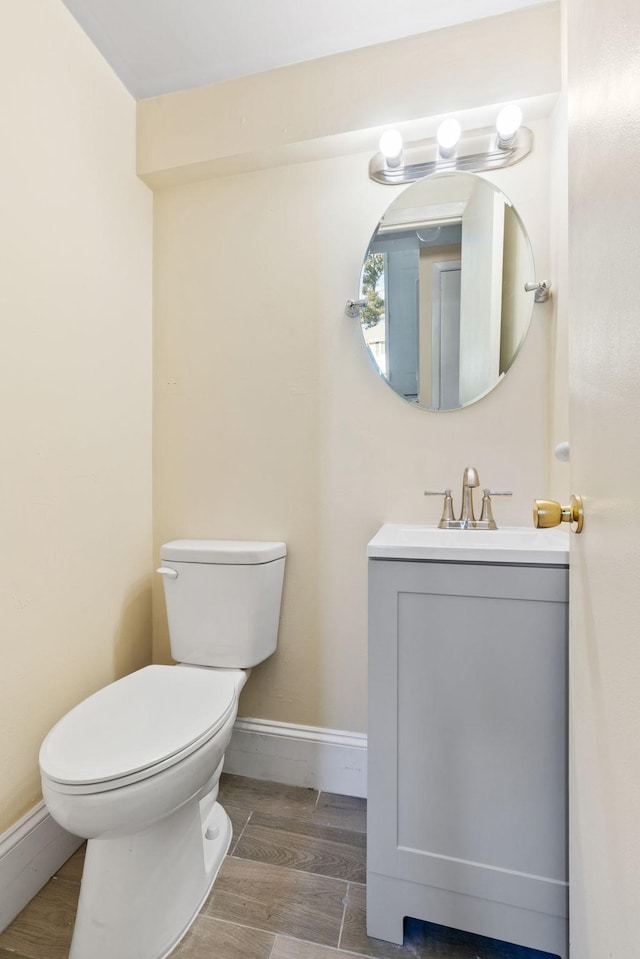 half bath with baseboards, vanity, toilet, and wood tiled floor