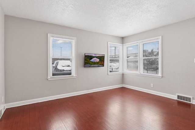 spare room with hardwood / wood-style floors, a healthy amount of sunlight, visible vents, and baseboards