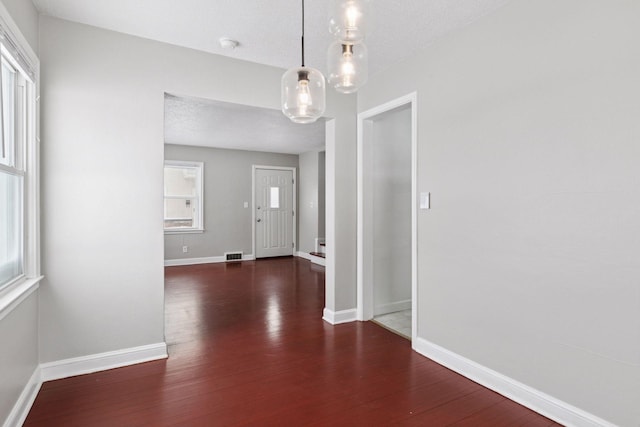 foyer featuring visible vents, wood finished floors, baseboards, and a textured ceiling