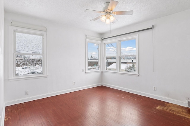 empty room with ceiling fan, a textured ceiling, baseboards, and wood-type flooring