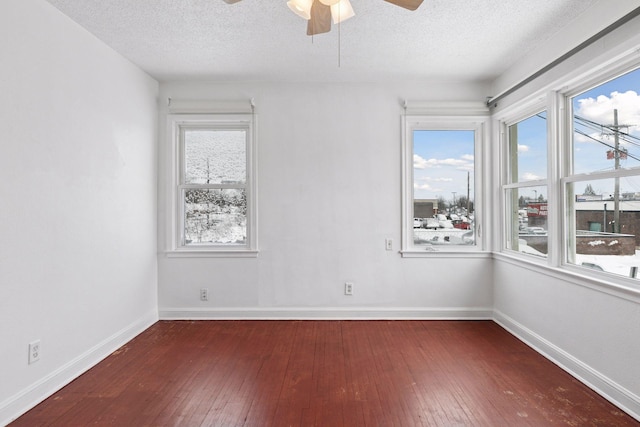 unfurnished room with a wealth of natural light, a ceiling fan, baseboards, and hardwood / wood-style flooring