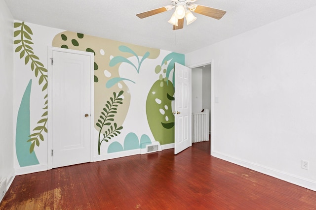 empty room with ceiling fan, visible vents, baseboards, and wood finished floors