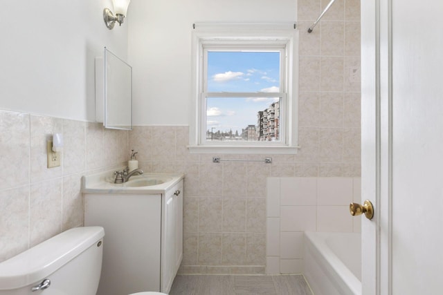 bathroom featuring toilet, tile walls, vanity, and a washtub