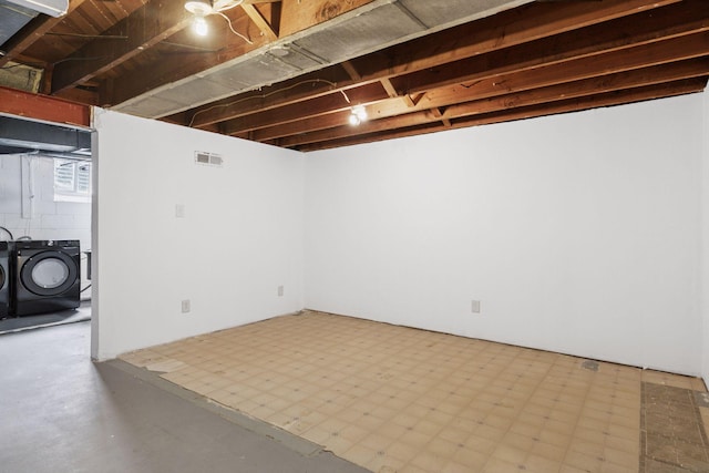 basement with tile patterned floors, visible vents, and washing machine and clothes dryer