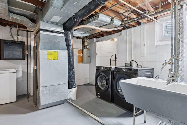 washroom with a sink, electric panel, heating unit, washing machine and dryer, and laundry area