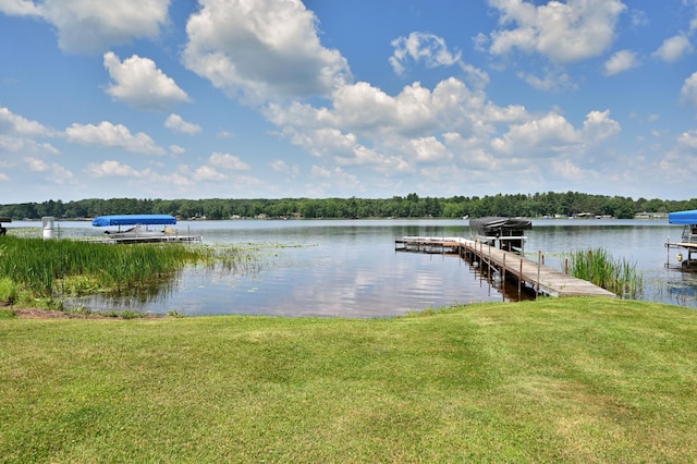 view of dock with a lawn and a water view