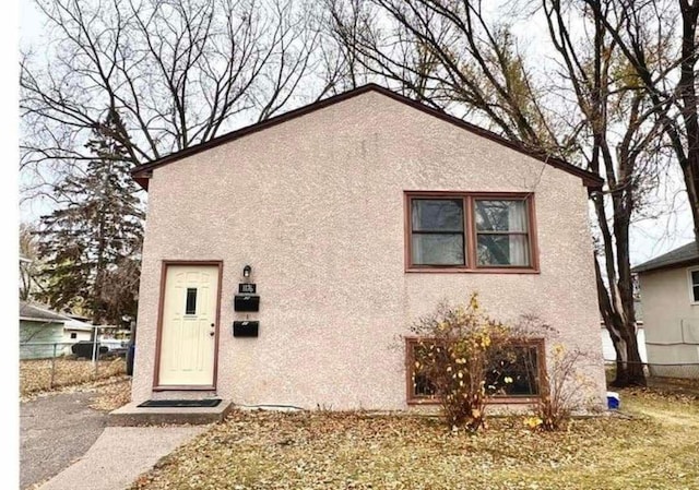 view of front facade with fence and stucco siding