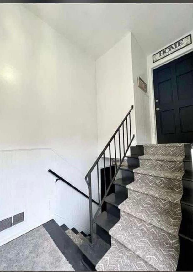 stairway with visible vents and wainscoting