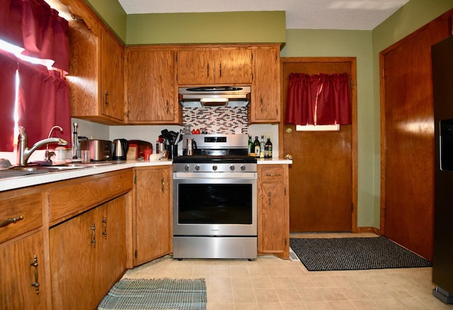 kitchen with brown cabinetry, stainless steel gas range, a sink, extractor fan, and light countertops