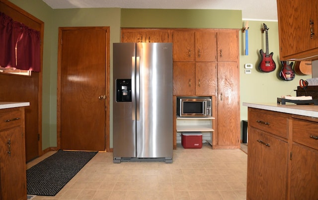 kitchen with brown cabinets, appliances with stainless steel finishes, and light countertops