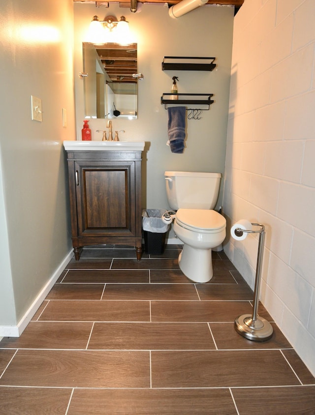 bathroom with vanity, toilet, baseboards, and wood tiled floor