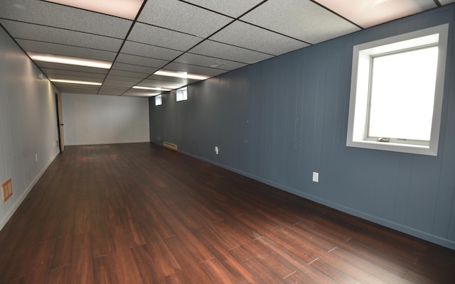 below grade area featuring plenty of natural light, wood finished floors, visible vents, and a paneled ceiling