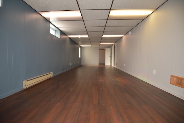 spare room with visible vents, a baseboard heating unit, baseboards, a drop ceiling, and wood finished floors