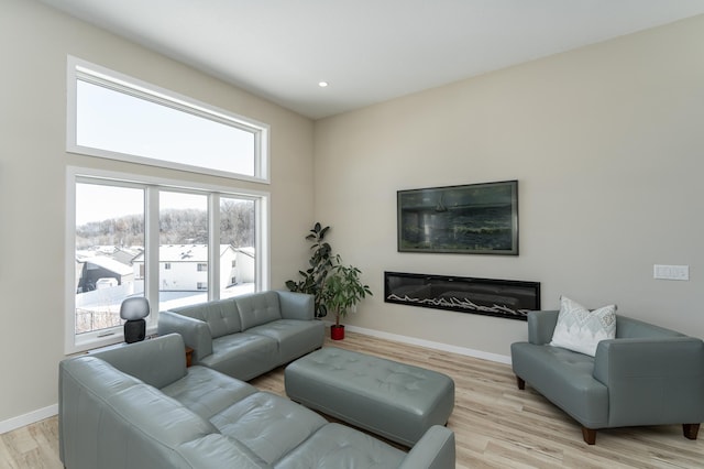 living room featuring recessed lighting, baseboards, and light wood finished floors