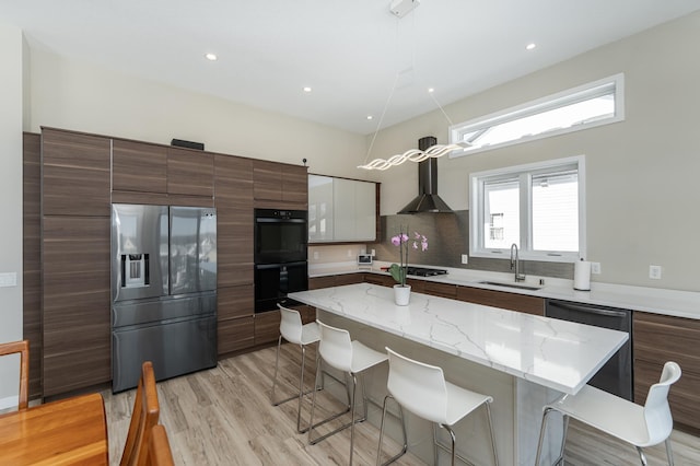 kitchen with tasteful backsplash, appliances with stainless steel finishes, light wood-style floors, a sink, and a kitchen breakfast bar