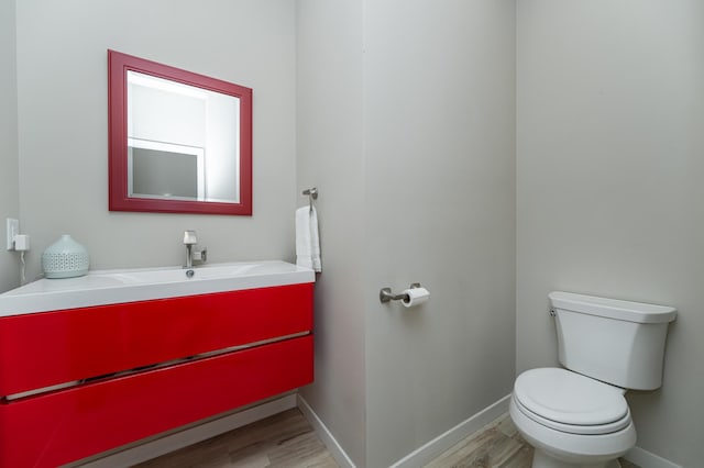 bathroom with toilet, baseboards, wood finished floors, and vanity