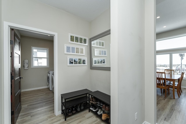 mudroom with baseboards, plenty of natural light, light wood finished floors, and washing machine and clothes dryer