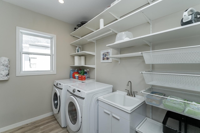 laundry area with washer and dryer, a sink, light wood-type flooring, laundry area, and baseboards