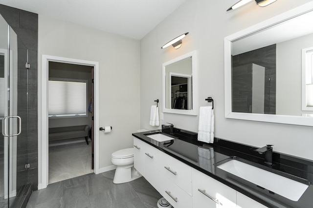 bathroom with double vanity, a shower stall, a walk in closet, and a sink