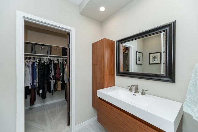 bathroom featuring baseboards, a spacious closet, vanity, and recessed lighting