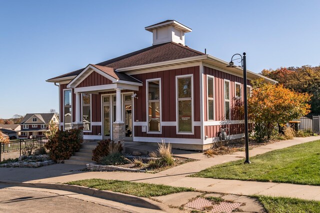 view of front of property featuring board and batten siding, fence, and a shingled roof