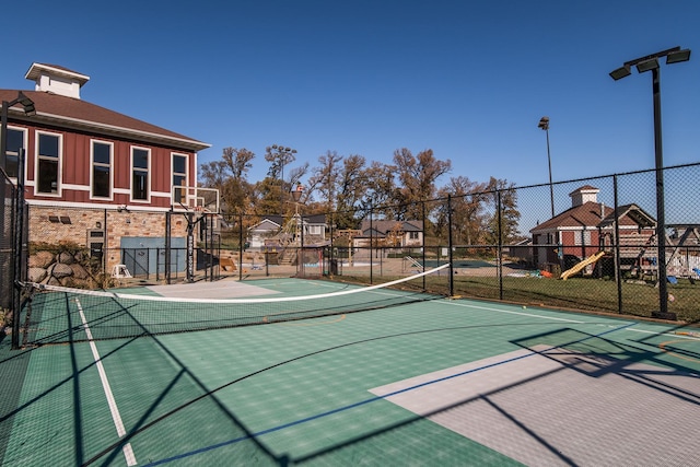 view of tennis court with a residential view, playground community, community basketball court, and fence