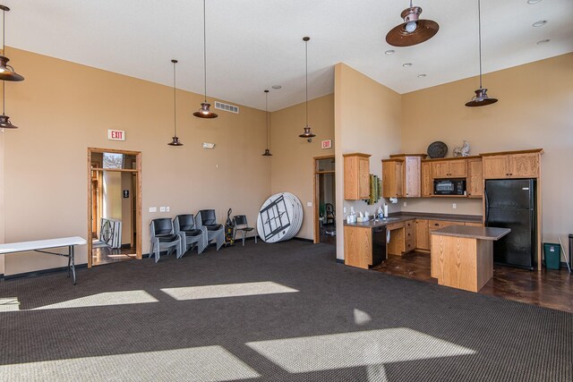 kitchen with a center island, visible vents, a towering ceiling, open floor plan, and black appliances