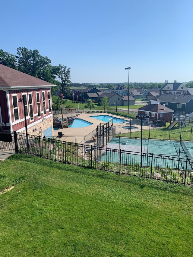 pool featuring a residential view, fence, and a lawn